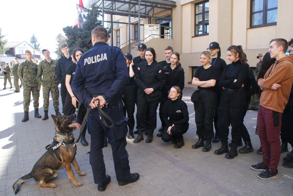 policyjny przewodnik z psem służbowym oraz grupa młodzieży w czasie spotkania  