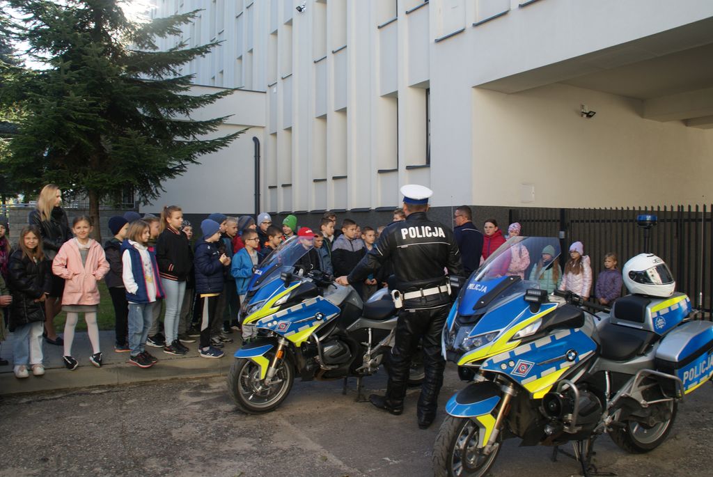 grupa dzieci oglądająca policyjne motocykle oraz mówiący do dzieci policjant 