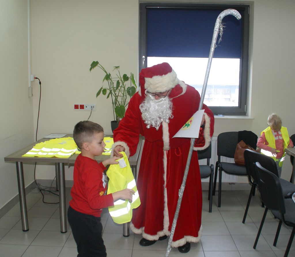 Mikołaj daje dziecku kamizelkę odbalskową 