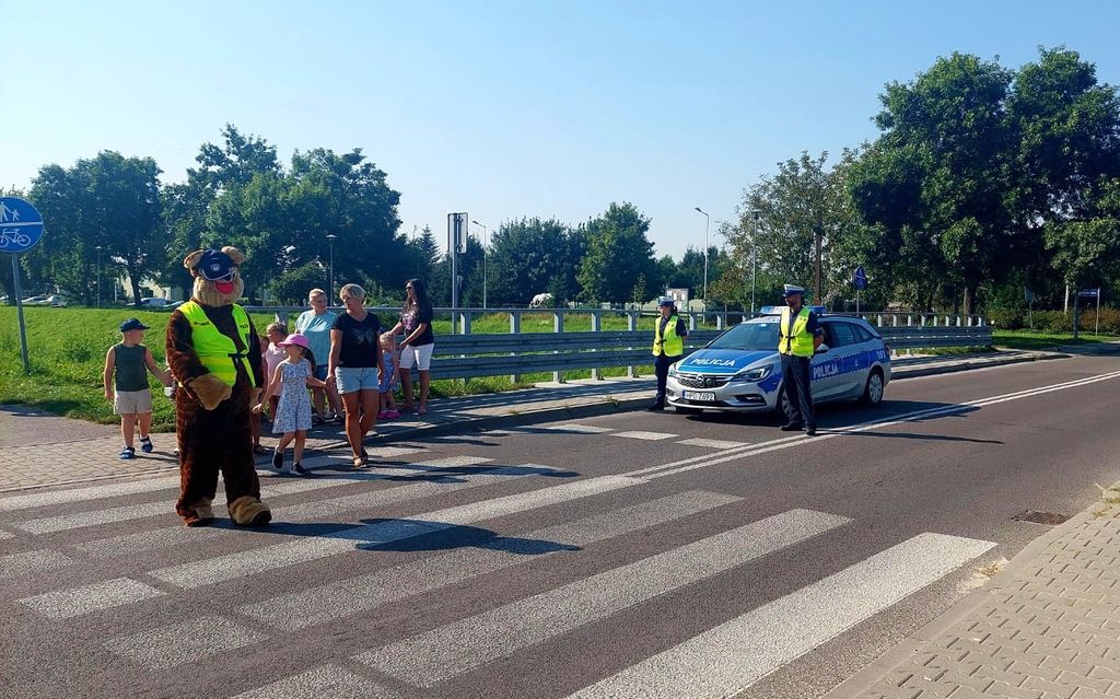 policyjna maskotka i dzieci przechodzą przez przejście 