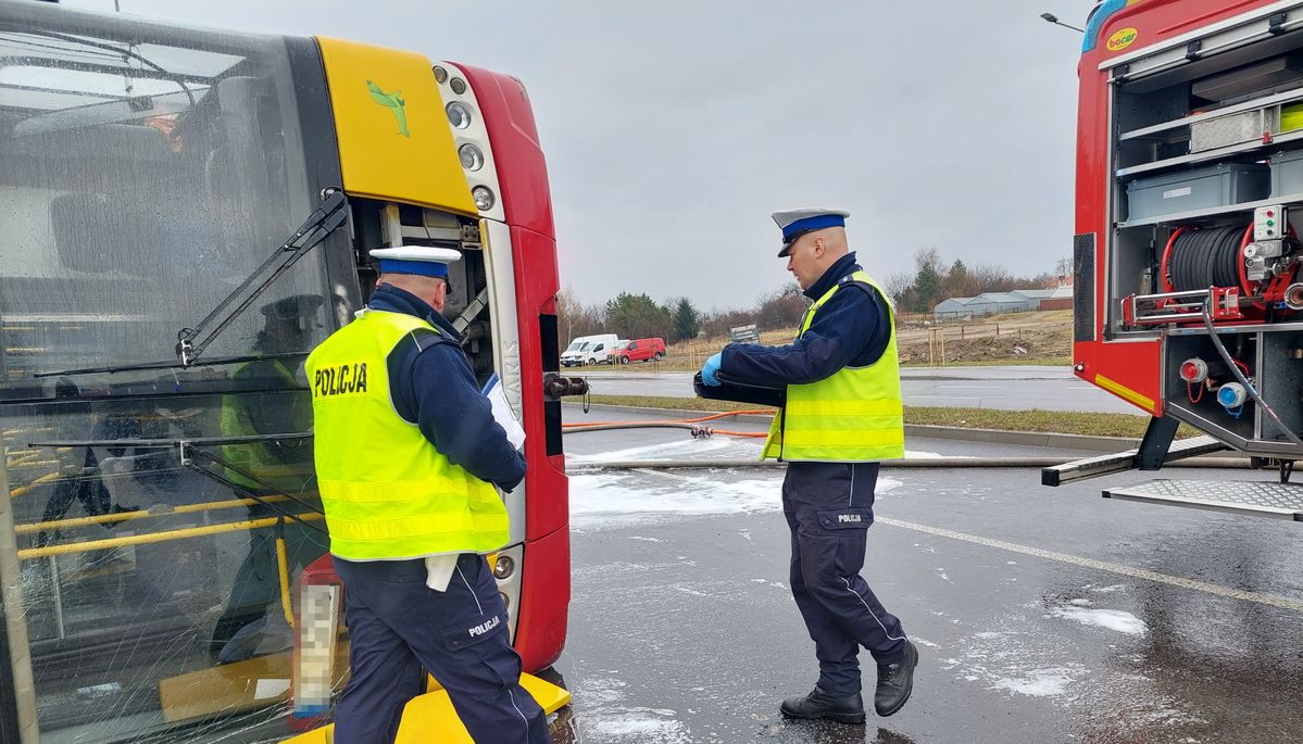 policjanci ruchu drogowego przy leżącym na boku autobusie 