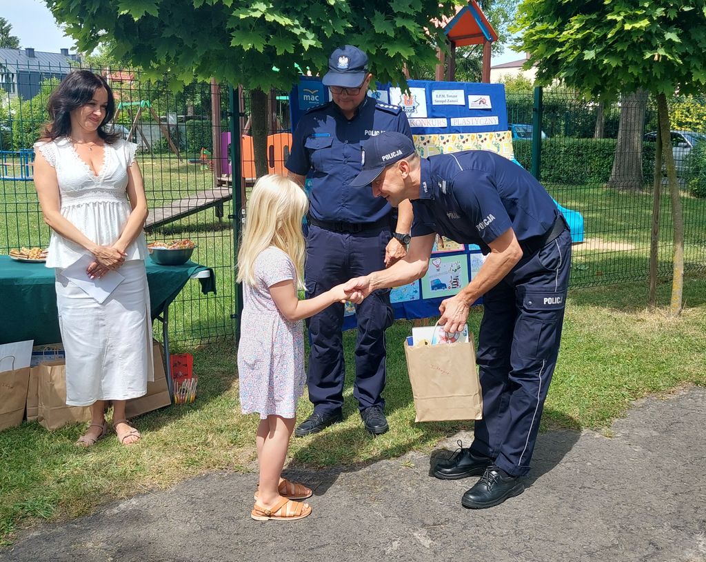 policjant wręcza nagrodę przedszkolakowi 