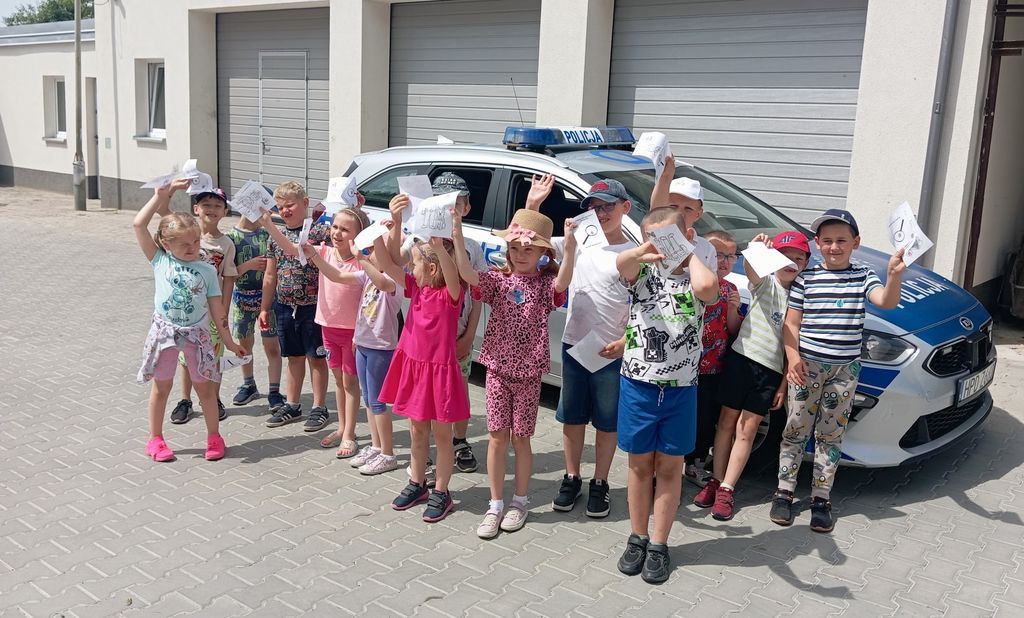 zdjęcie zbiorowe policjantka z dziećmi na tle radiowozów 