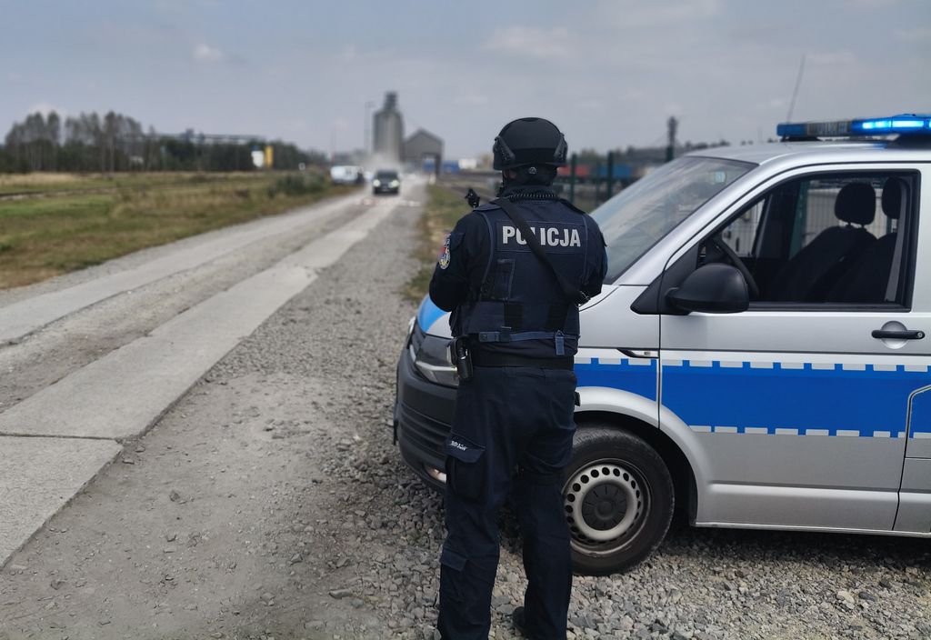 policjant stojący obok radiowozu