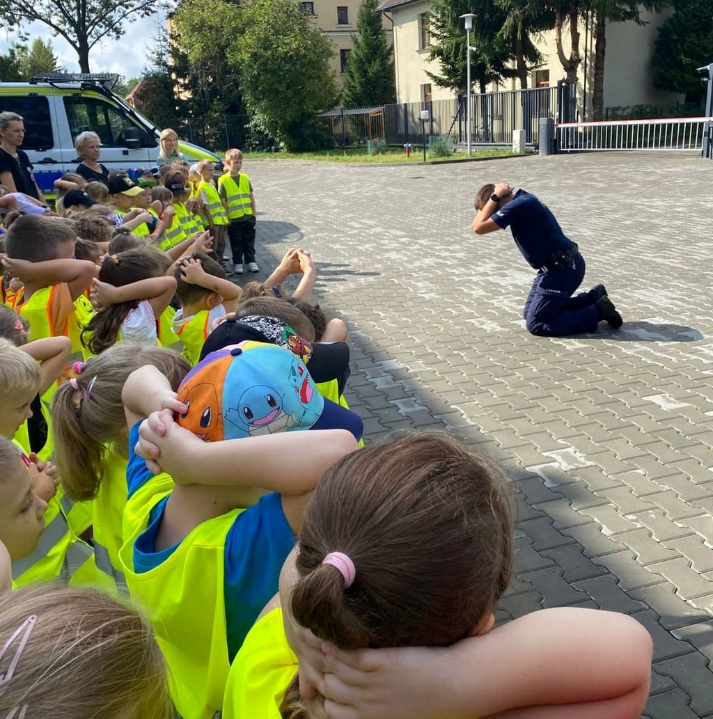 policjant pokazuje dzieciom pozycję żółwia 