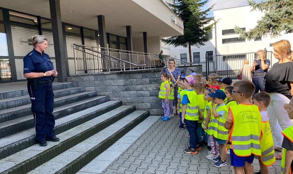 dzieci i policjantka przed budynkiem komendy 
