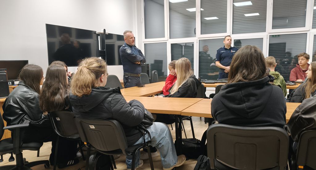 policjant mówi do siedzącej przy stołach młodzieży 