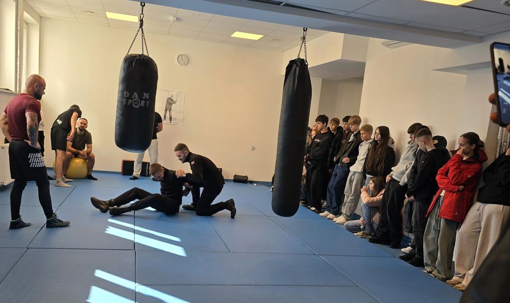 policjanci w strojach sportowych oraz młodzież ćwiczą na matach