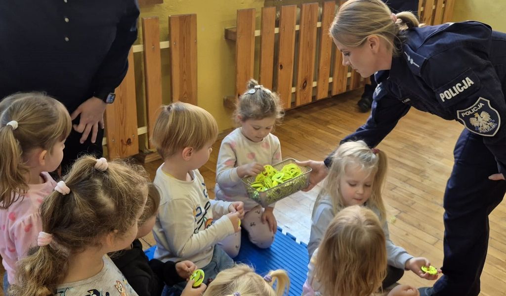 policjantka rozdaje dzieciom odblaskowe breloczki
