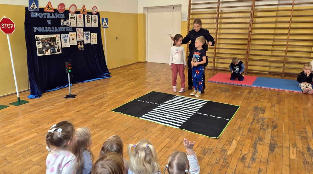 policjantka w sali przedszkola ćwiczy z dziećmi właściwe przechodzenie przez jezdnie