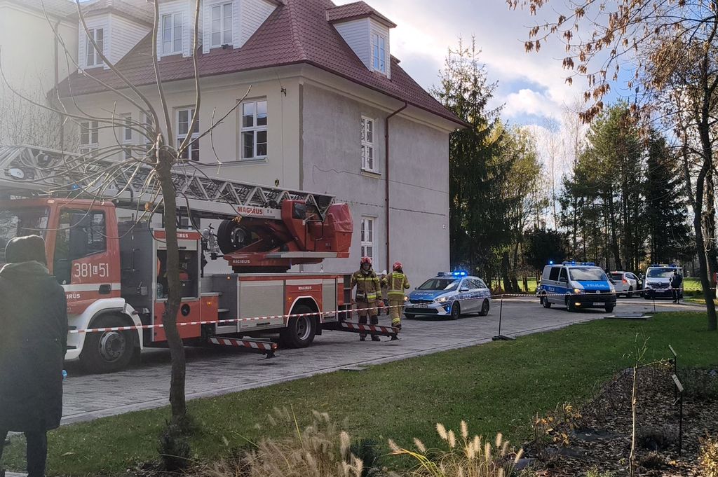 ćwiczenia, budynek szkoły przed którym stoi wóz strażacki i radiowóz 