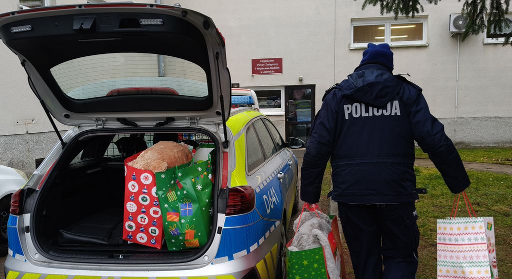 policjantka wyjmuje z bagażnika radiowozu prezenty dla dzieci 
