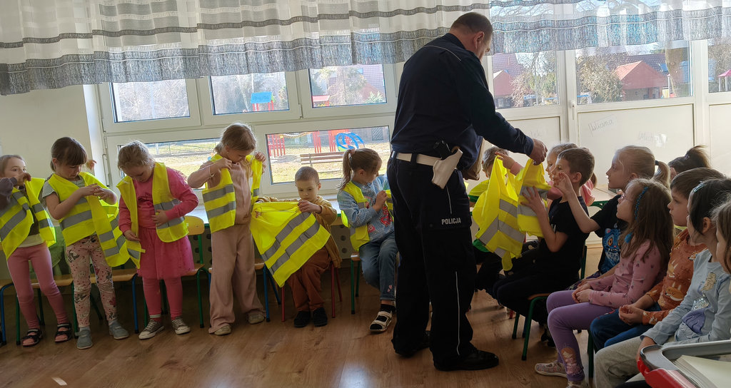 policjant rozdaje dzieciom kamizelki odblaskowe 