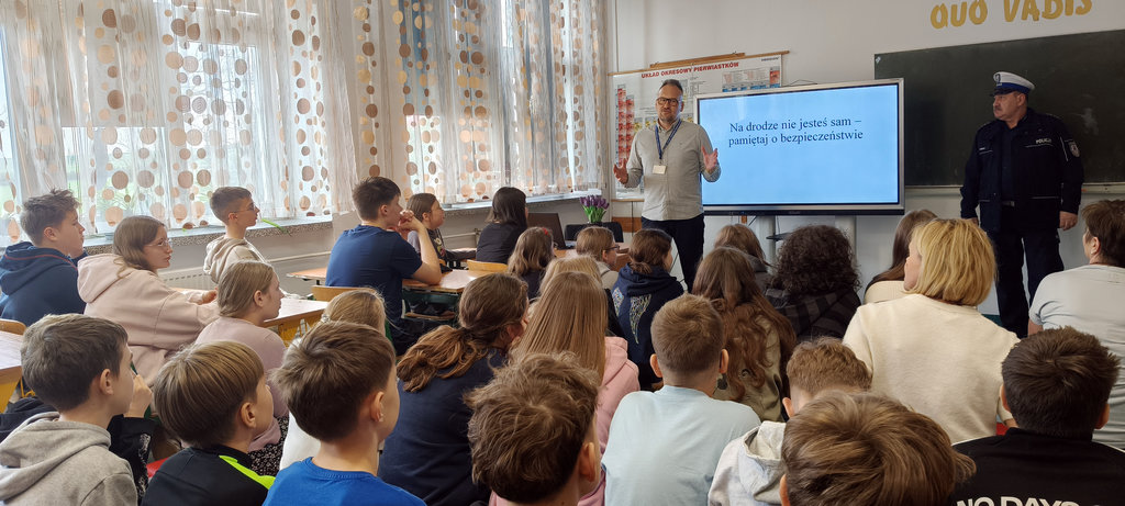 Pracownik Wojewódzkiego Ośrodka Ruchu Drogowego i policjant rozmawiają z uczniami o bezpieczeństwie drogowym