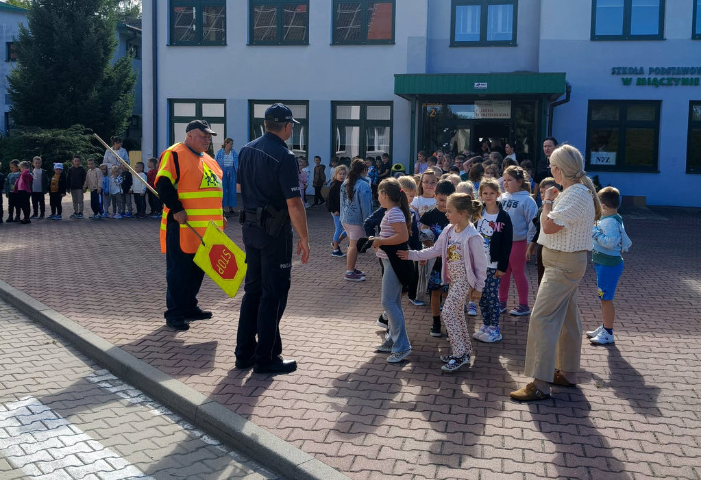 policjant z dziećmi przed szkołą 