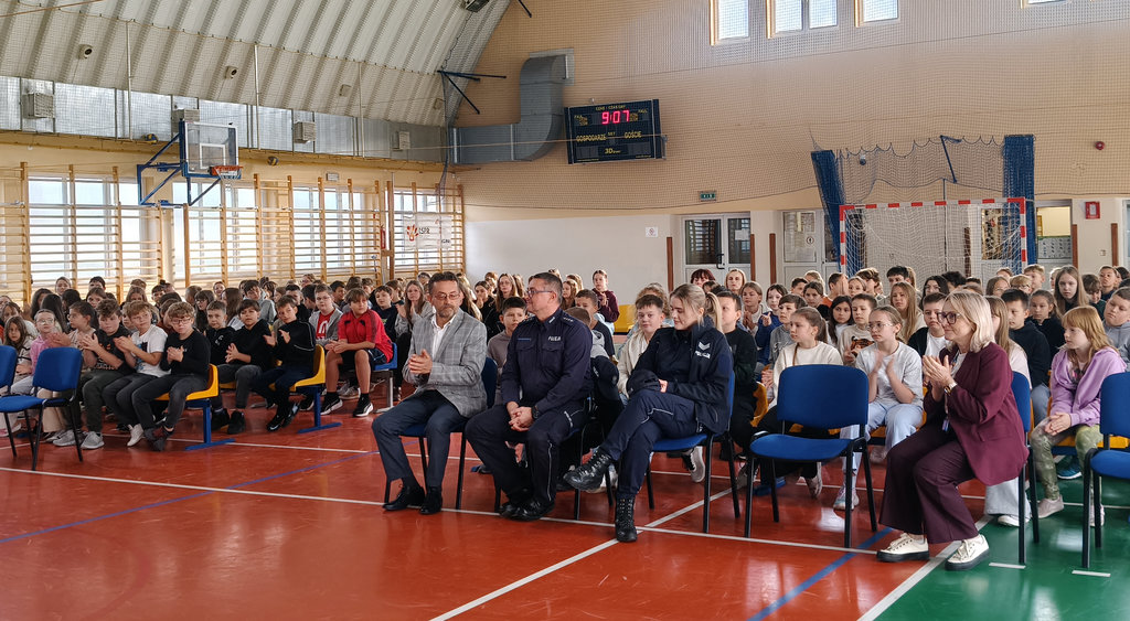 sala gimnastyczna, na krzesłach siedzą uczniowie