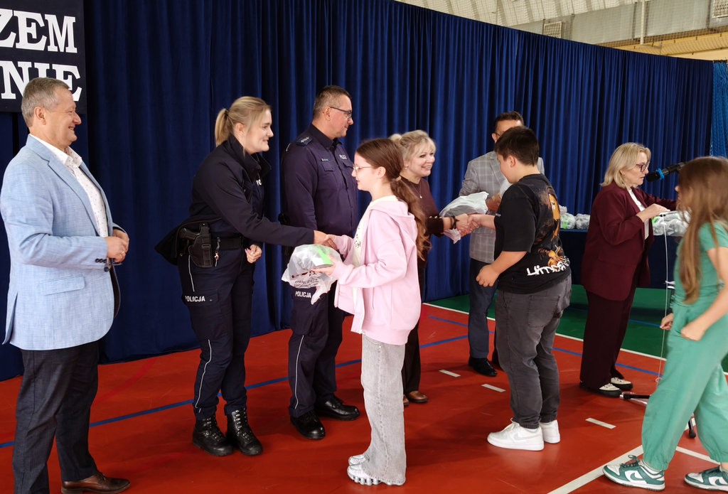 policjanci i przedstawiciele kuratorium wręczają dzieciom kaski rowerowe