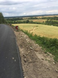 pole z uprawą zboża, na którym widoczna jest droga jazdy samochodu, w oddali auto, które jechało po polu