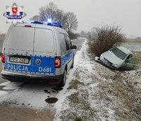 stojący na drodze policyjny radiowóz, w rowie rozbity opel