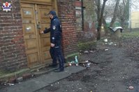 policjant przed drzwiami opuszczonego budynku