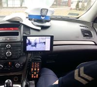 wnętrze policyjnego radiowozu, leżąca na kokpicie czapka policjantów z ruchu drogowego, ekran videorejestratora