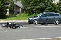 leżący na drodze rozbity motocykl, obok stojąca z rozbitym przodem toyota