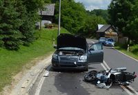 miejsce wypadku, na drodze stoi rozbita z przodu osobowa toyota a przed nią leży na jezdni motocykl