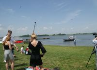 uczniowie i policjant na terenie plaży w Nieliszu w czasie kręcenia spotu, w tle na tafli wody policyjna łódź