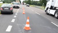 droga, stojący na poboczu osobowy mercedes, który uderzał w barierę ochronną, na przeciwnym poboczu fragment pojazdu ciężarowego, w tle inne samochody