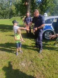 policjant w czasie pikniku rozdają dzieciom elementy odblaskowe