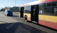 policjant wchodzący do autobusu, w tle radiowóz policyjny