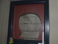 okno z rozbitą szybą i wewnętrzną kratą