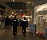 idący tyłem policjant i strażnik miejski na pasażu galerii handlowej