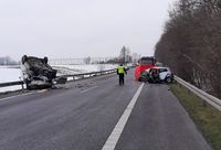 miejsce wypadku, leżące na dachu bus oraz osobowa toyota, na środku drogi stoi policjant