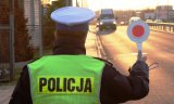 stojący tyłem na poboczu policjant z tarczą do zatrzymywania pojazdów