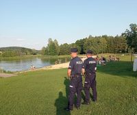 stojący nad brzegiem zalewu policyjny patrol