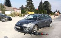 zdjęcie osobowego citroena i leżącego na drodze roweru, który częściowo znajduje się pod lewym przednim kołem samochodu