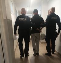 policjanci idą z zatrzymanym