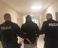 dwóch idących tyłem policjantów z zatrzymanym