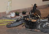 uszkodzona ściana budynku i leżący obok motocykl