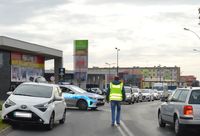 Idący środkiem jezdni nieumundurowany policjant. Na jednym pasie ruchu stoi policyjny radiowóz, a przed nim osobowa toyota. W tle różne samochody.