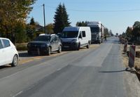 Dwa samochody osobowe, za nimi bus, a za busem ciężarówka. Wszystkie samochody stoją na poboczu wzdłuż jednego pasa drogi.