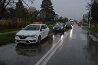 Droga, przejście dla pieszych. Przed pasami stoi osobowe renault, za przejściem nieoznakowany radiowóz, w tle inne pojazdy.