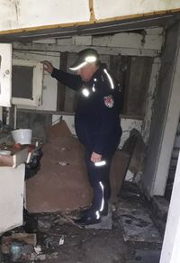 policjant w opuszczonym domu sprawdza, czy nie mieszkają tam bezdomni