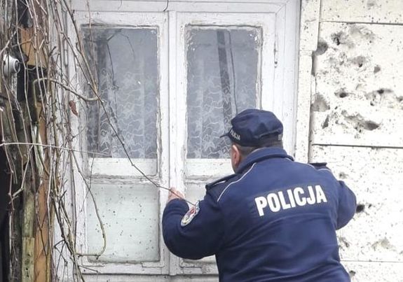policjant zaglądający przez okno do pustostanu