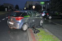 Stojący we wjeździe na teren parkingu osobowy Citroen i leżąca obok niego hulajnoga elektryczna. W tle stojące na parkingu dwa inne pojazdy.