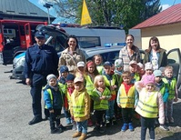 zdjęcie grupowe policjanta i dzieci wraz z opiekunkami podczas Dnia Otwartego OSP, w tle radiowozy policyjne