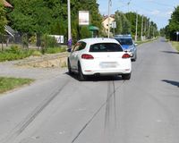 osobowy volkswagen stojący tyłem na drodze, przed nim widoczne na drodze ślady hamowania