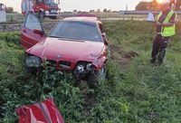 pojazd osobowy w przydrożnym rowie, obok stoi policjant