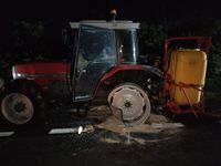 stojący na jezdni ciągnik rolniczy z opryskiwaczem uszkodzony w wyniku zderzenia z pojazdem osobowym